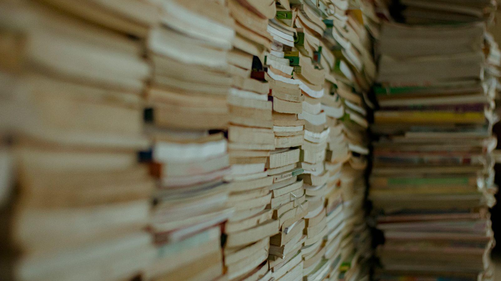 Masada üst üste dizilmiş ciltli akademik kitap yığını