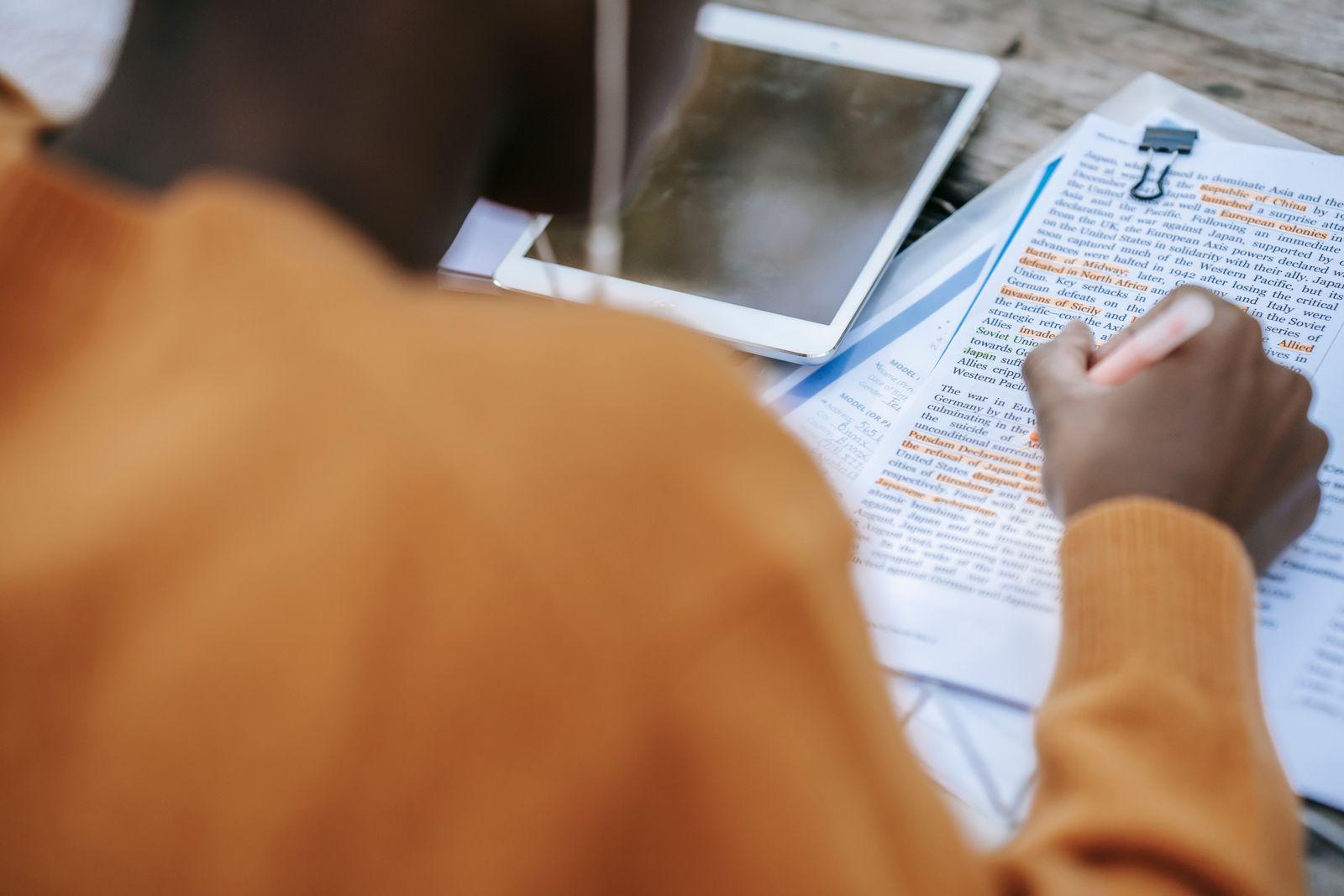 Kulaklık takıp kağıt üzerinde metni işaretleyen kişi, yanında tablet